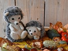 two knitted animals sitting on top of leaves next to pumpkins and acorns