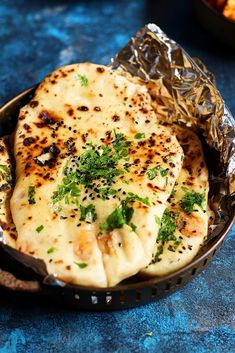 some food that is sitting in a pan on a blue counter top with tin foil