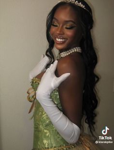 a woman in a green dress and white gloves smiles at the camera while wearing a tiara