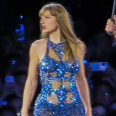 a woman in a blue dress holding an umbrella on the runway at a fashion show