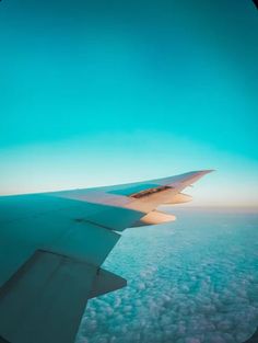 the wing of an airplane as seen from above in the sky, with clouds below