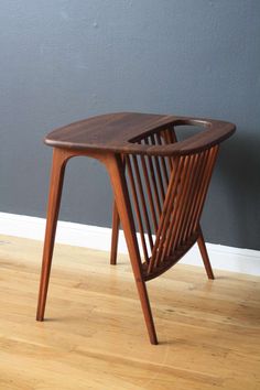 a small wooden table sitting on top of a hard wood floor next to a gray wall