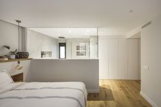 a bedroom with white walls and wood flooring next to a bed in front of a mirror