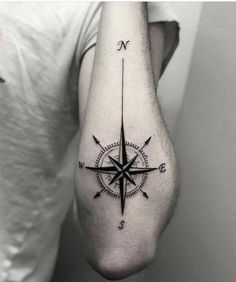 a black and white photo of a man's arm with a compass tattoo on it