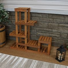 a set of wooden shelves next to a potted plant and lantern on the floor