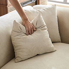 a person reaching for a pillow on a couch