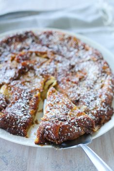 a cake with powdered sugar on top sitting on a plate next to a fork