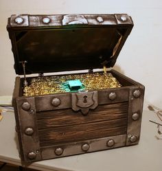 an open chest with gold coins in it on a table next to glasses and other items