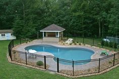 an above ground pool surrounded by a fenced in area with a gazebo and hot tub