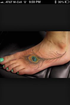 a woman's foot with a peacock feather tattoo on the top and bottom of it