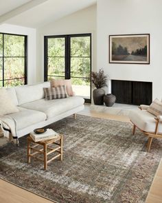 a living room filled with furniture and large windows next to a fire place in the corner