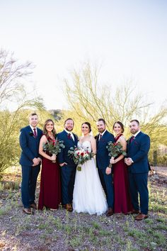 a bride and groom with their bridal party in front of the desert tree line