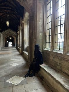 a woman sitting on top of a stone floor next to a window filled with windows