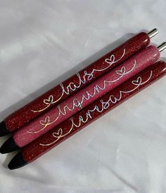 three pens with writing on them sitting on top of a white sheeted tablecloth