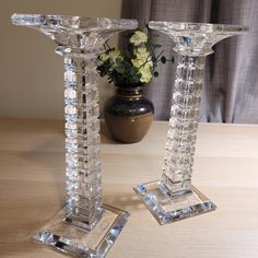 two crystal candlesticks sitting on top of a wooden table next to a vase with flowers