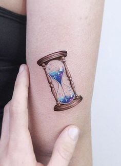 a woman's arm with a tattoo on it that has an hourglass in it