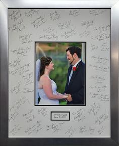 a couple holding hands and looking at each other with autographs written on the wall behind them