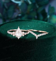 two diamond rings sitting on top of a green velvet box