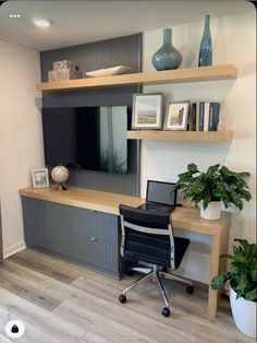 a desk with a laptop on top of it in front of a wall mounted tv