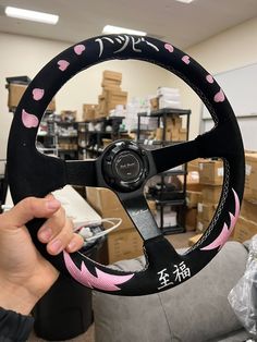 a person holding up a steering wheel cover with pink hearts on it in a room full of boxes