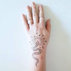 a woman's hand with a snake tattoo on her left wrist and stars in the background