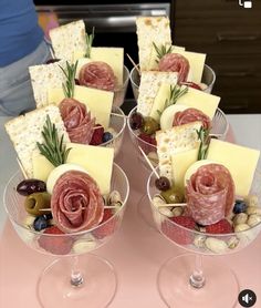 two wine glasses filled with different types of cheese and meats on top of each other