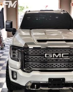 the front end of a white gmc truck on a checkered floor in a garage