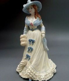 a ceramic figurine of a woman in a dress and hat