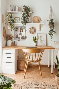 a wooden desk topped with lots of potted plants next to a wall mounted bookshelf