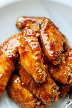 chicken wings covered in bbq sauce on a white plate