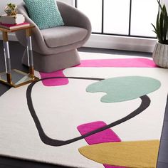 a living room area with a chair, rug and potted plant on the floor