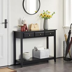 a black console table with two vases on it and a round mirror above it