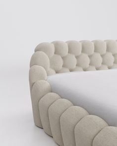 an upholstered bed with white sheets and buttons on it's headboard