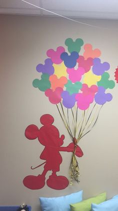 a room with a bed and mickey mouse balloon decoration on the wall, next to a couch