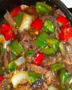 a skillet filled with beef, peppers and onions