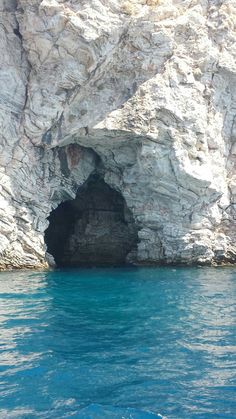 a cave in the side of a mountain with blue water