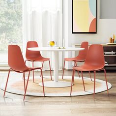 a white table with four orange chairs around it and a painting hanging on the wall