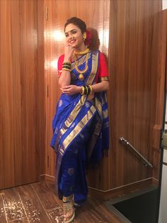 a woman in a blue and gold sari standing next to a wooden paneled wall