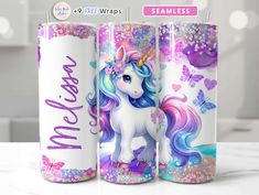 three unicorn tumbles with glitter and butterflies on them, one has a rainbow mane