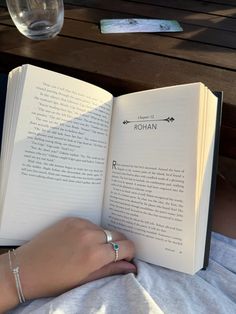 a person is reading a book on a bed with their hand resting on an open book