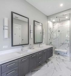 a large bathroom with two sinks, mirrors and a shower stall in the middle of it