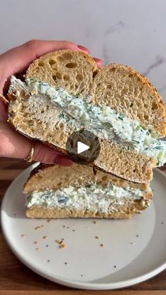 a person holding a sandwich on top of a white plate