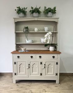 an old dresser is painted white and has potted plants on top