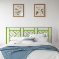 a bed with white sheets and green headboard in front of two pictures on the wall