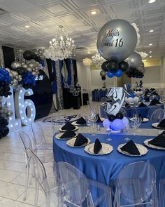 a blue and silver party with balloons, table cloths, chairs, and decorations