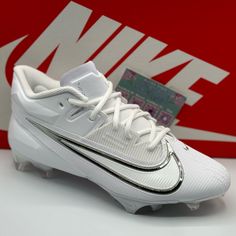 a pair of white and black nike soccer cleats in front of a red box