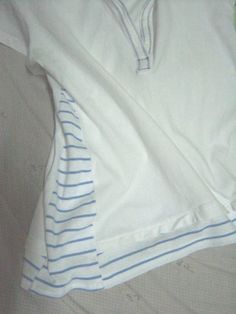 two white shirts laying on top of a bed next to each other with blue stripes