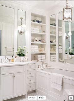 a bathroom with white cabinets and towels on the shelf next to the bathtub is shown