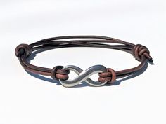 a brown leather bracelet with an infinite knot on it's end and a silver plated clasp