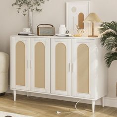 a white cabinet with wicker doors in a living room next to a chair and potted plant